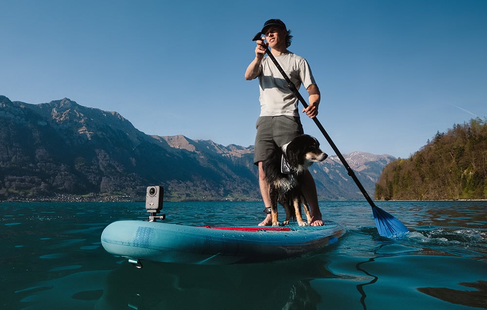man paddling with a dog on a SUP board with a sports camera attached