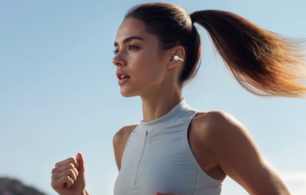 Woman running outdoors in sportswear and wireless headphones