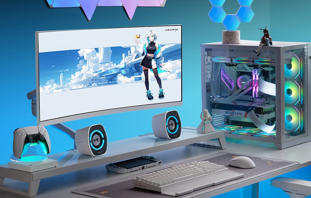Stůl zobrazující reproduktory, počítač, monitor se zobrazenou hrou a konzoli.