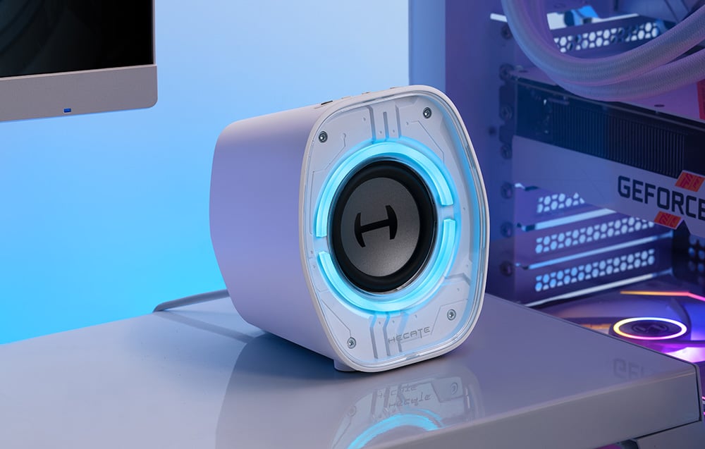 Detailní záběr bílého reproduktoru Hecate s podsvícením ležícího na stole.