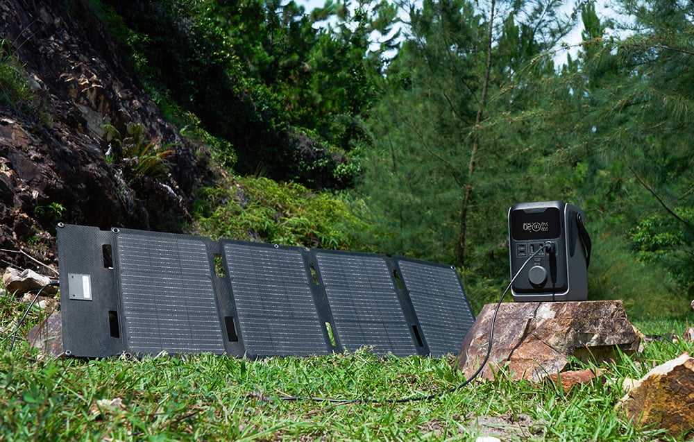 A photovoltaic panel connected to a portable power station standing on a rock in the woods