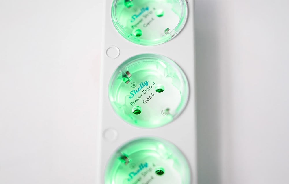 Close-up of a white Shelly Power Strip 4 extension cord with green-lit outlets labeled Gen4