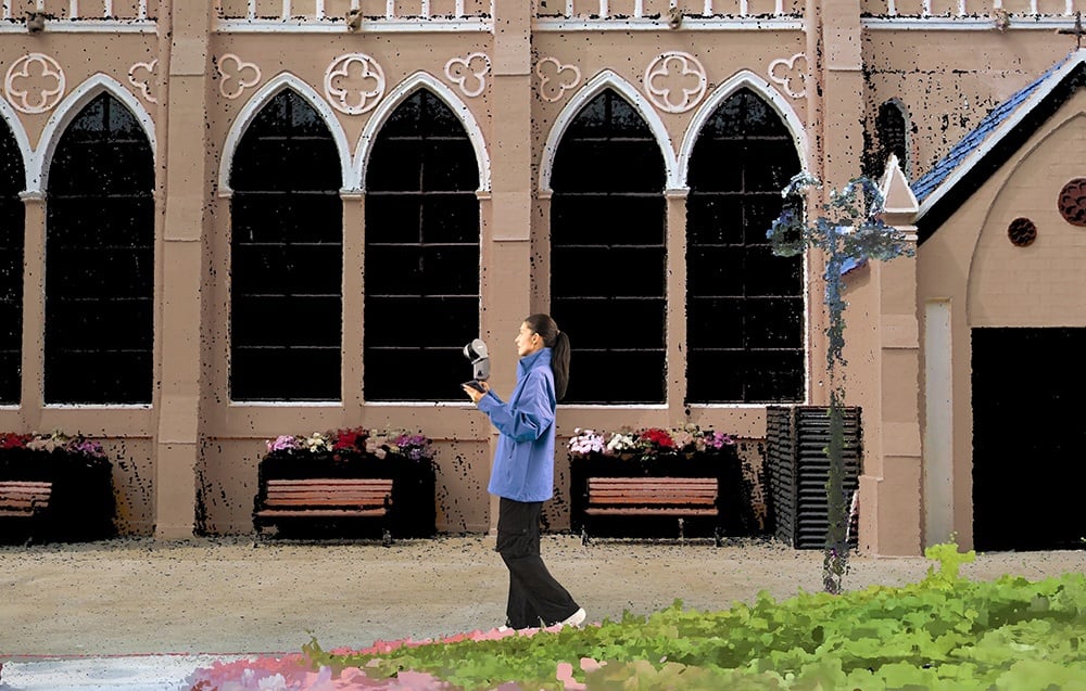 A woman stands next to a large building with a mobile 3D scanner.