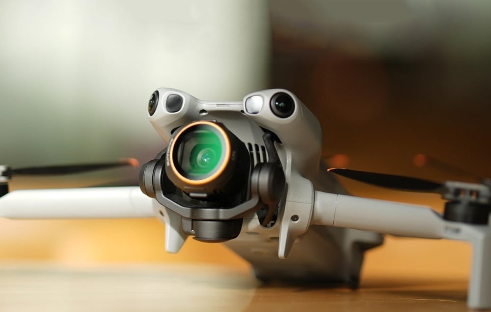 DJI Mini drone with visible camera with green lens and orange ring standing on table