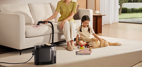 Laps mängib põrandal kassiga ja ema tolmuimejaga heledat diivanit elutoas