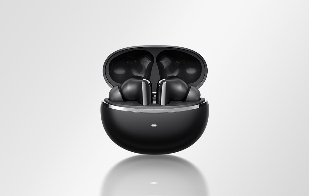 Mustad traadita kõrvaklapid avatud mustas laadimiskarbis heledal taustal