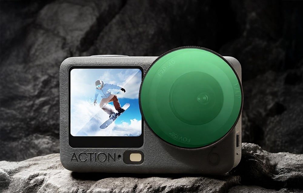 Sports camera with green protective filter installed, lying on a rock.