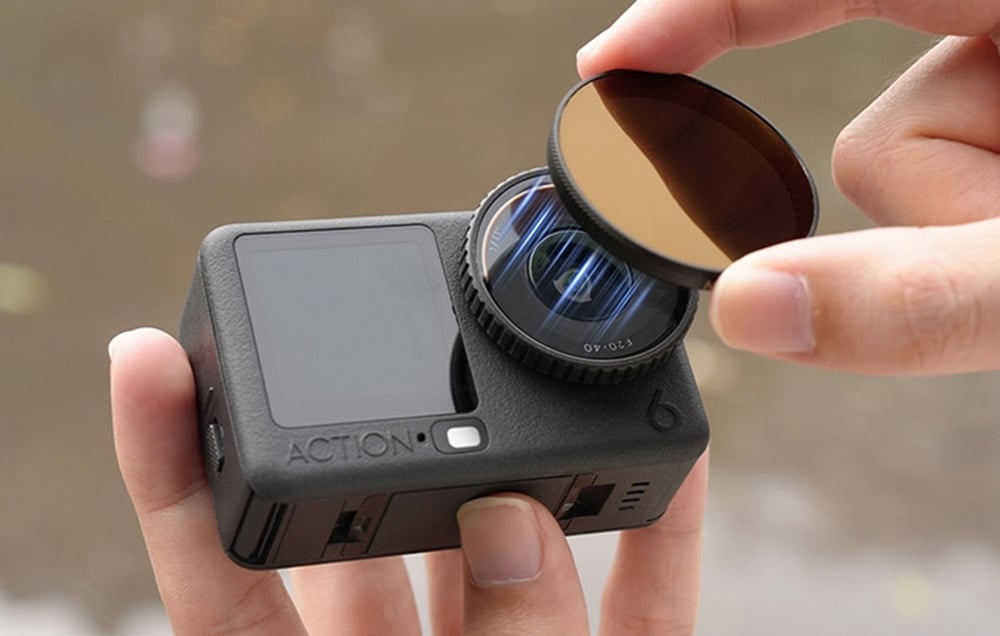 Close-up of mounting a protective filter on the lens of a sports camera held in the hand