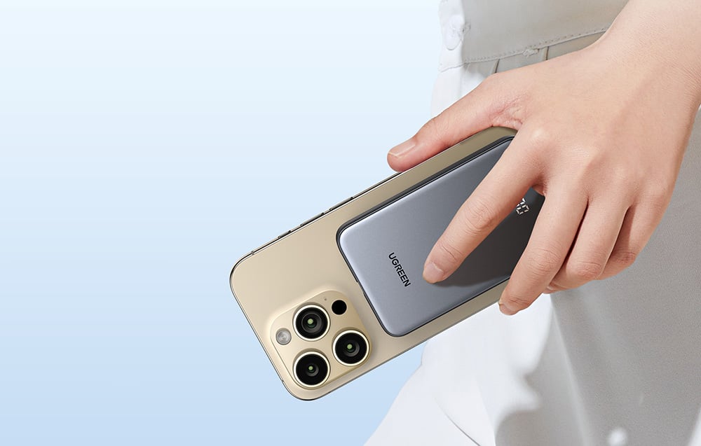 Kéz, amely egy mágnesesen rögzített Ugreen power bankkal ellátott okostelefont tart.