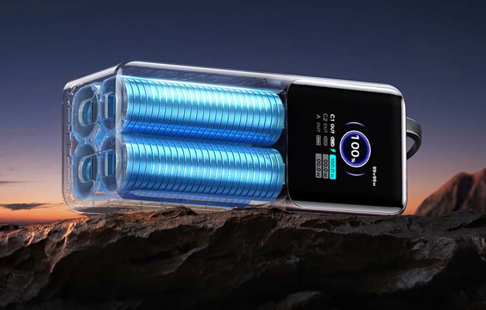 A power bank belsejének vizualizációja kék akkumulátorcellákkal, szürkületkor sziklás talajon elhelyezve.