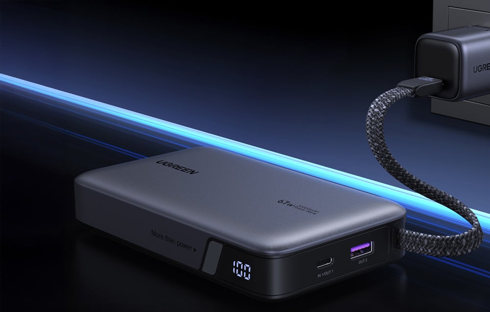 Ugreen power bank falitöltőhöz csatlakoztatva. Látható digitális kijelző, amely 100% töltöttséget és USB-C és USB-A portokat mutat.