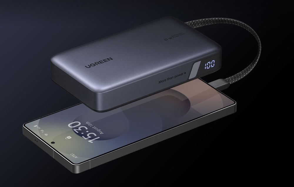 Közelkép az Ugreen 67W power bankról, amely egy okostelefont tölt. A készülék oldalán jól látható az akkumulátor állapotát jelző kijelző.