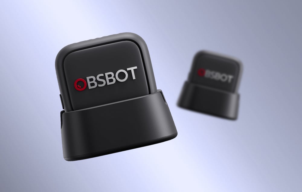 Two OBSBOT microphones on charging stands captured in dynamic perspective, one sharp in the foreground and the other blurred in the background