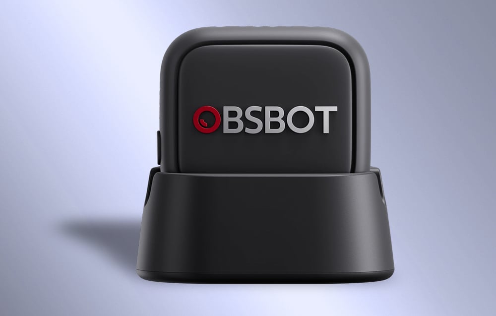 OBSBOT microphone in a black housing placed on a charging base with a visible logo on the front panel