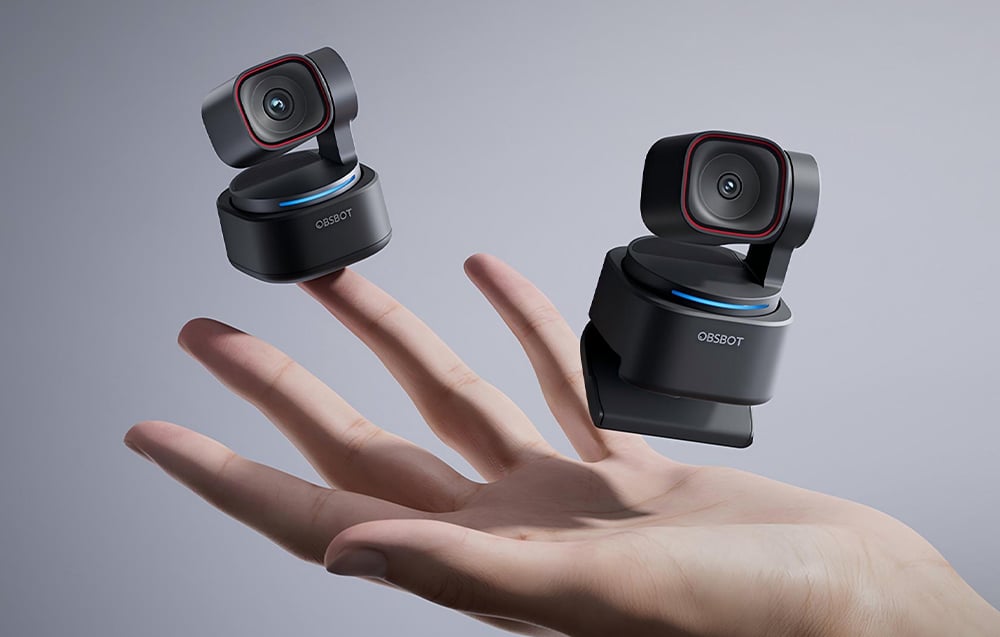 Dwie kompaktowe kamery internetowe OBSBOT z obrotową podstawą unoszą się nad otwartą dłonią
