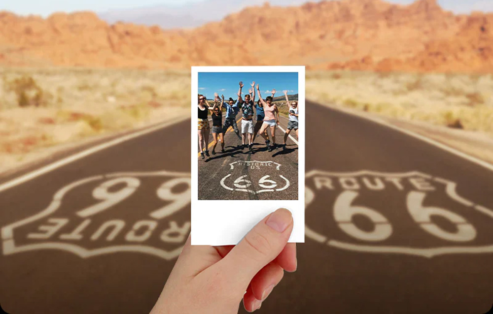 Hand holding a printed photo with Route 66 in the background