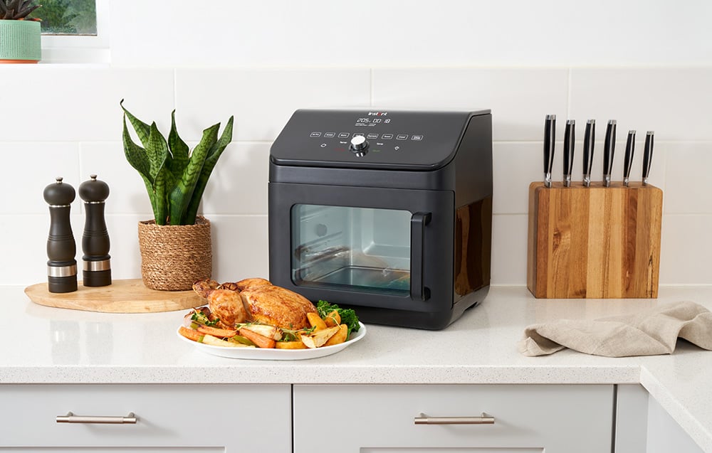 Pieczony kurczak z warzywami leży na talerzu przed zamkniętym czarnym piekarnikiem