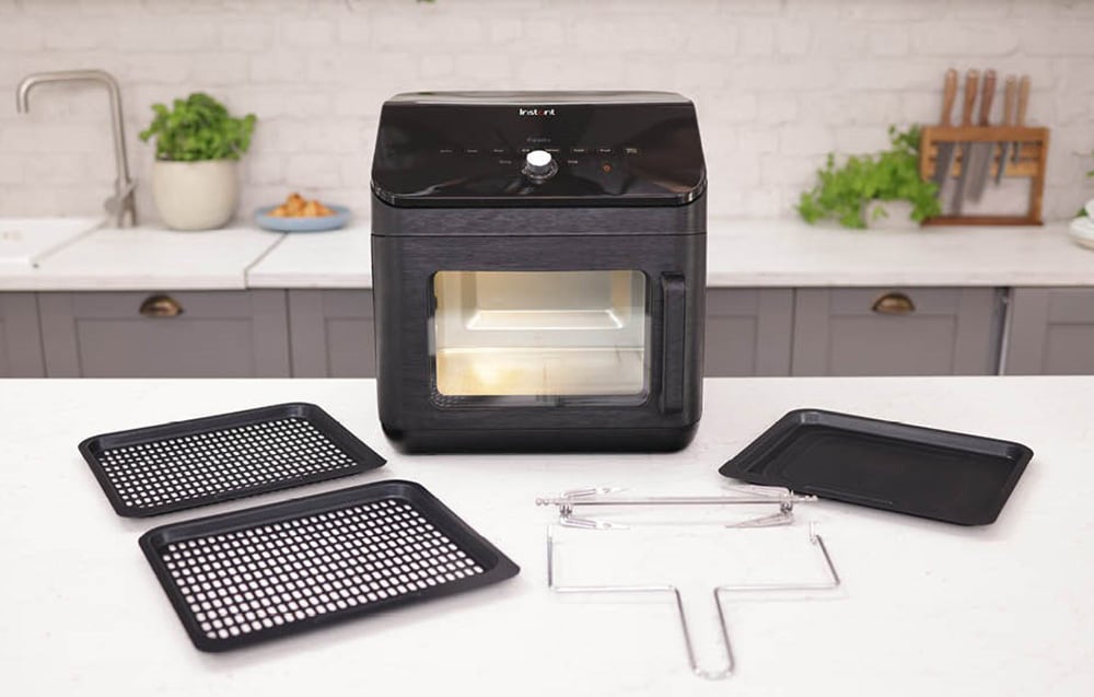 Czarny piekarnik stoi na blacie obok wyjętych z niego akcesoriów, takich jak blaszki