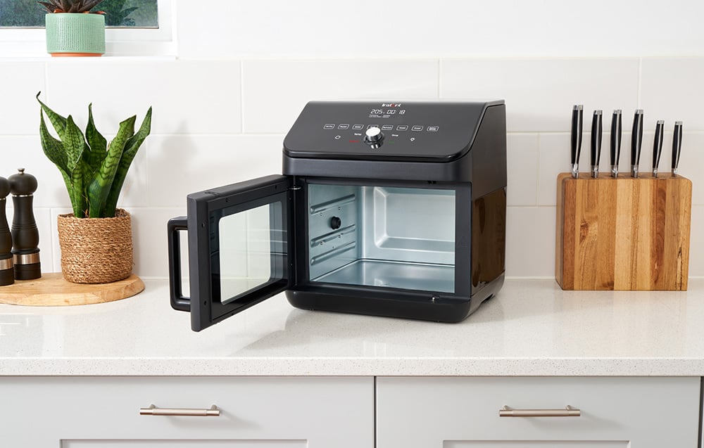 Otwarty, pusty czarny piekarnik stoi na kuchennym blacie