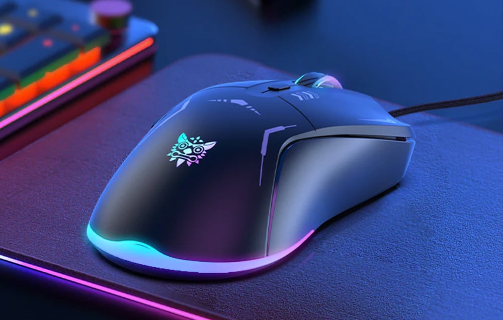 The ONIKUMA wired mouse with backlight lies on the desk next to the keyboard