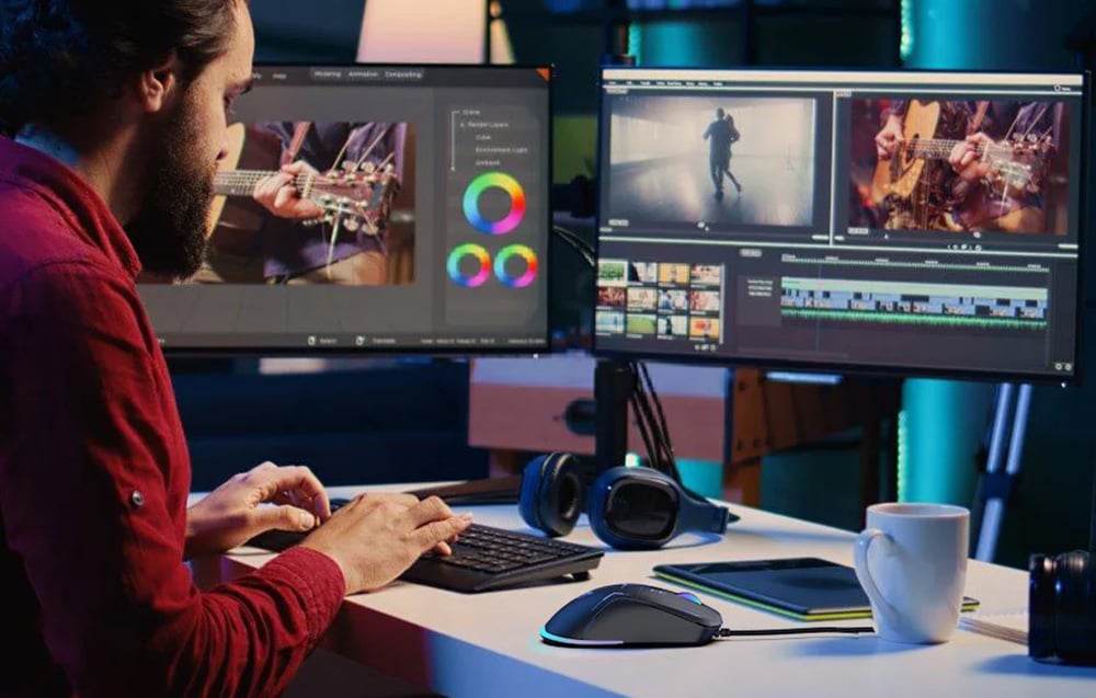 A man works at a desk with several monitors, next to it lies a keyboard and mouse