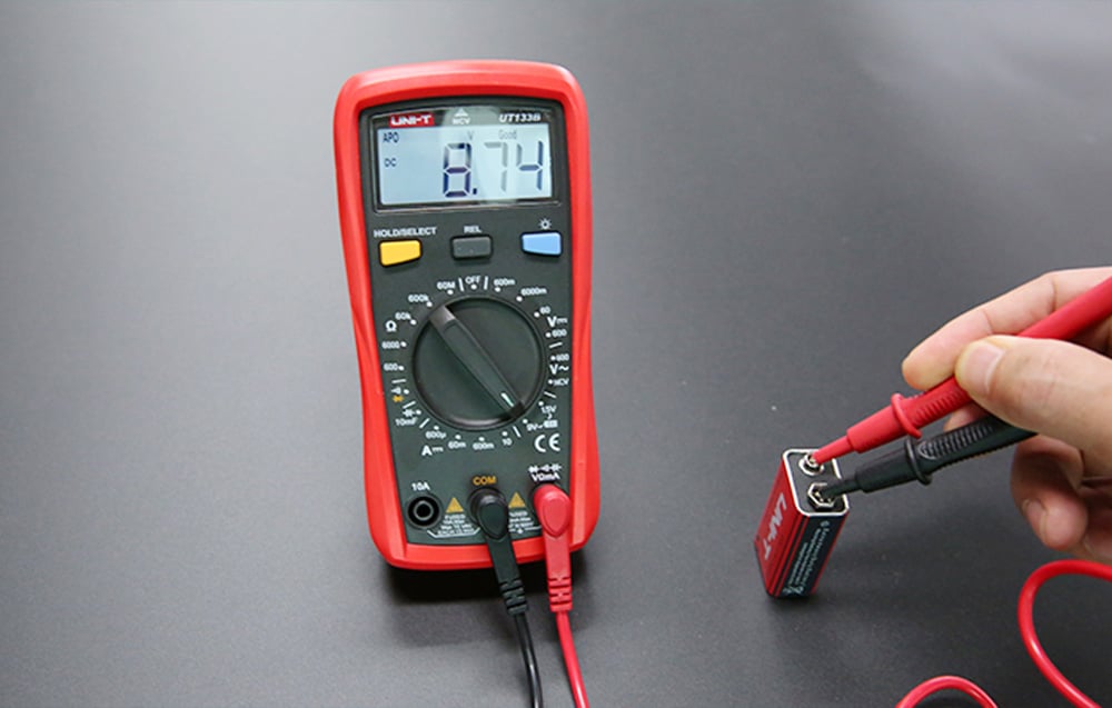 Testing the voltage level of a battery pack using the multimeter’s red and black test probes.