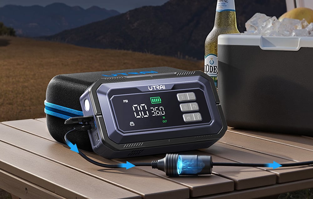 A car jump starter powers a cooler standing on a wooden table.
