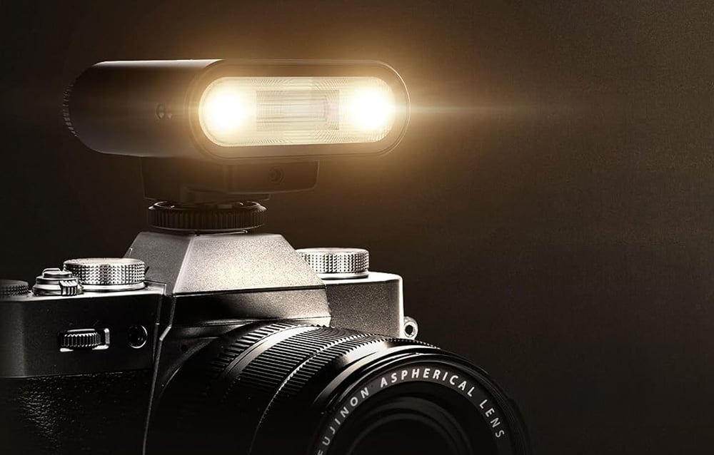 A camera with a flash emitting a warm beam of light from two points.