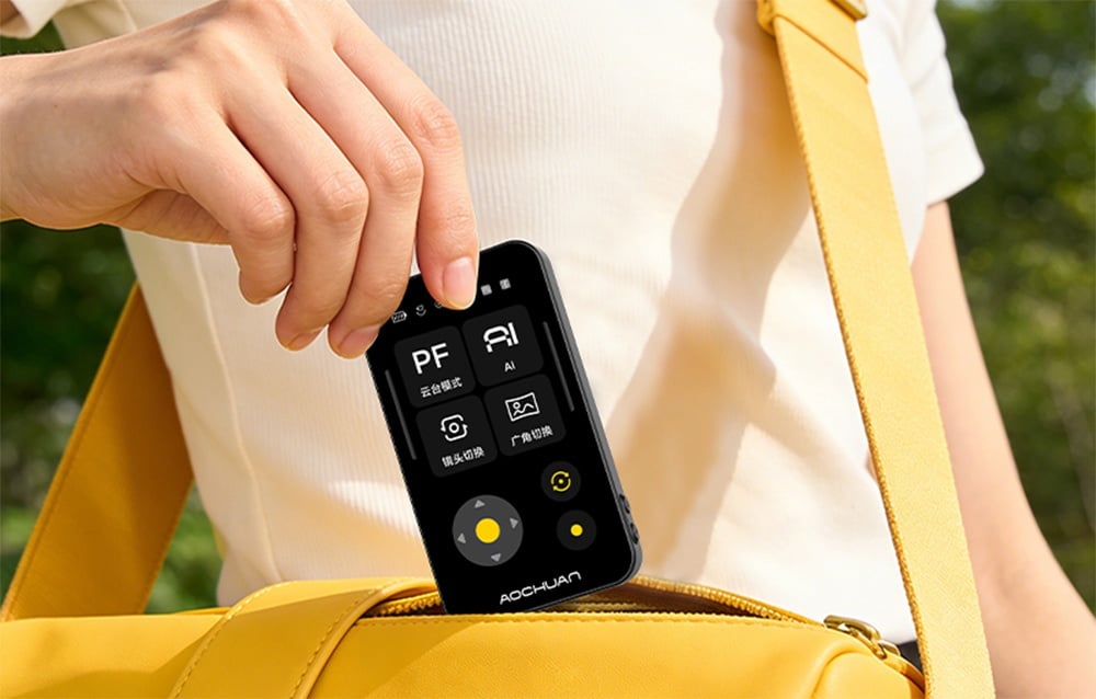 Black module with an LCD display for the Aochuan Smart X Pro gimbal being taken out of a yellow waist bag