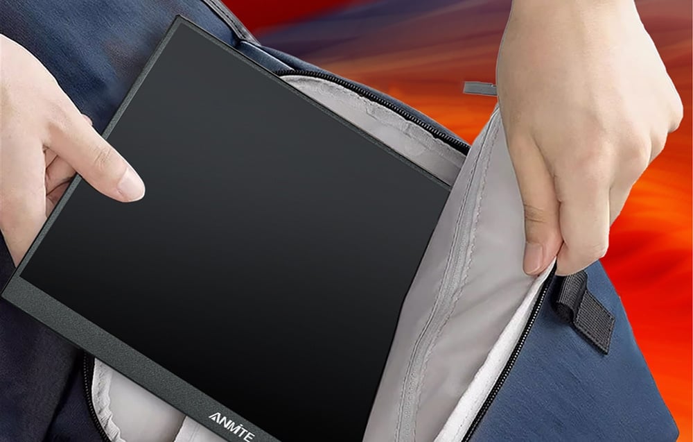 Hands tucking a flat, black monitor into a blue travel bag.