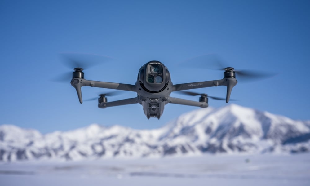 Dron DJI Mavic 4 Pro w locie na tle zimowego krajobrazu