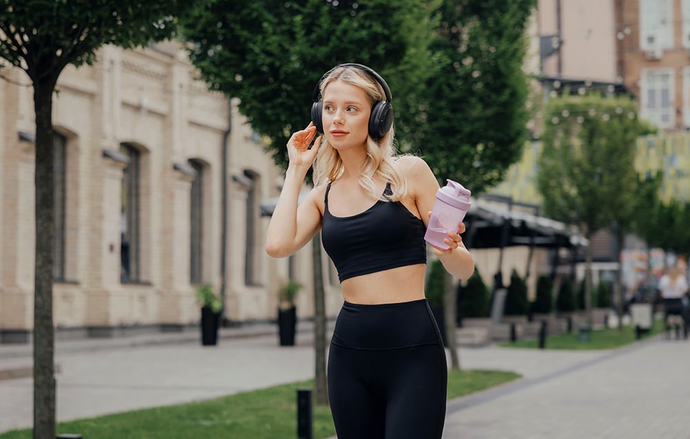blondynka w sportowym czarnym stroju z czarnymi słuchawkami nausznymi