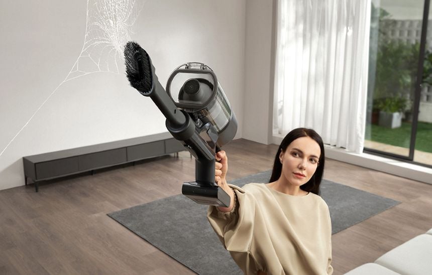 Kobieta używająca odkurzacza ręcznego Dreame do czyszczenia pajęczyny na ścianie